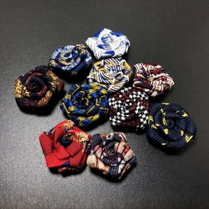 Close-up of handmade fabric rose suit pins in mixed colors for elegant suit lapels