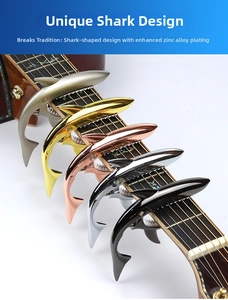 Five colored zinc alloy shark guitar capos clamped on a guitar neck fingerboard closeup