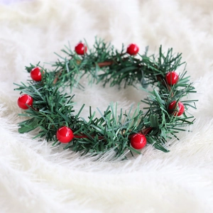 Christmas candle ring with red berries and green pine needles on white plush background