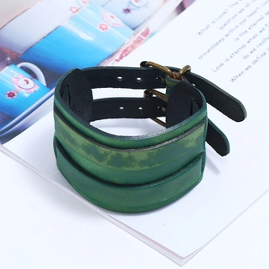 Detail of vintage green leather wide bracelet with bronze double buckles on book pages