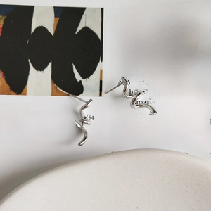 Macro shot of spiral 925 sterling silver stud earrings on a ceramic dish and book