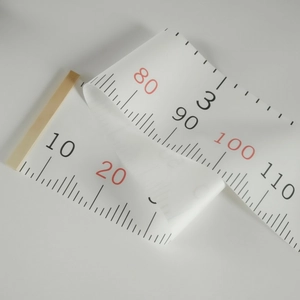 Close-up of flexible measuring tape with black and red markings on white background