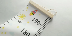 Detail of wooden hanger and rope with colorful rocket patterns on canvas height chart