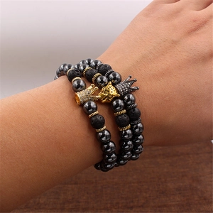 Detail of hematite bead bracelet set with gold leopard head and crown charms on wrist