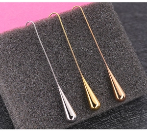 Detailed view of long teardrop earrings in silver, gold, and rose gold finishes