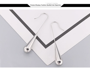 Detailed macro view of silver teardrop dangle earrings with a high-polished mirror finish
