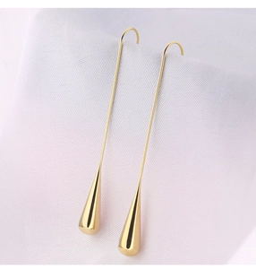 Detailed view of elegant golden teardrop earrings on white textured fabric background