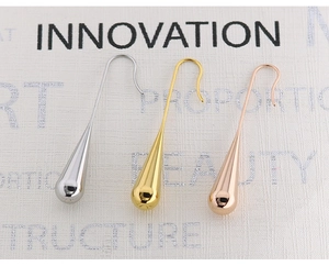 Detailed view of teardrop earrings in silver, gold and rose gold finishes on fabric