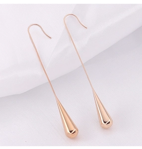 Close-up of rose gold teardrop dangle earrings on soft white silk fabric background