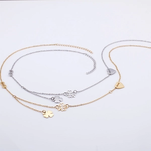 Fashionable gold and silver waist chains with clover and heart pendants on white background
