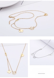 Detail of layered steel necklace with heart, clover, and infinity charms in gold and silver