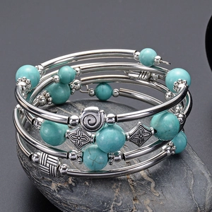 Detail of turquoise beads and vintage metal charms on a multi-layer elastic wrap bracelet