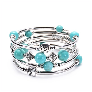 Detail of multi-layer turquoise bead bracelet with vintage silver-tone metal charms