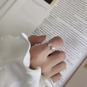 Close-up of 925 sterling silver irregular star ring worn on finger with artistic background