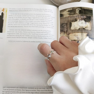 Irregular jagged silver ring shown on a finger over an open book with minimalist style