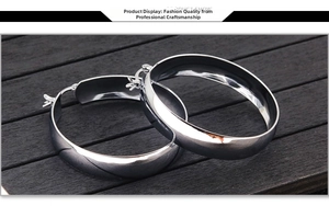 Macro detail of wide flat silver stainless steel hoop earrings with polished mirror finish