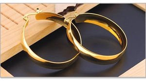 Detailed view of polished wide chunky gold hoop earrings with mirror finish texture