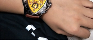Close-up of yellow triangle dial automatic watch with brown leather strap on wrist