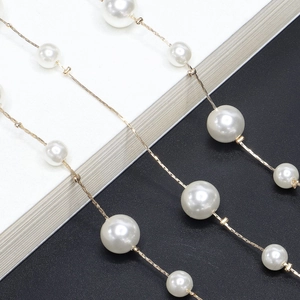 Detail of long gold chain necklace with alternating large and small white pearls