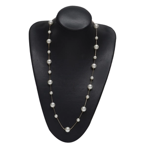 Elegant gold pearl necklace with various sized white pearls displayed on a black bust