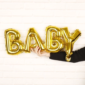 Macro detail of glossy gold BABY script foil balloon for birthday party backdrop decor