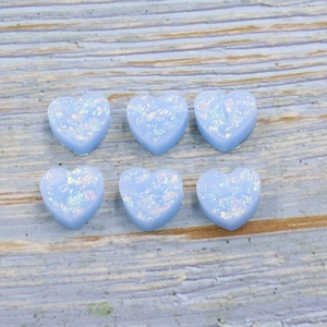 Light blue heart-shaped synthetic opal resin beads with iridescent glitter on wood