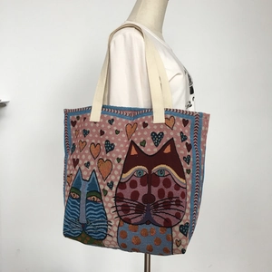Detail of artistic cat tapestry tote bag with thick woven handles shown on a mannequin