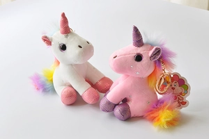 Close-up of pink and white plush unicorn keychains with rainbow manes and glitter details
