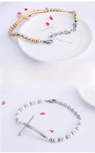 Close-up of fine steel cross bracelets with 18K gold plating and pearl details