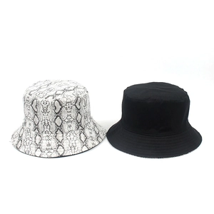 Detail view of reversible bucket hats in black-and-white snake print and classic solid black