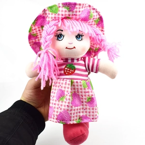 Detail of embroidered strawberry doll face with pink yarn braids and checkered sun hat