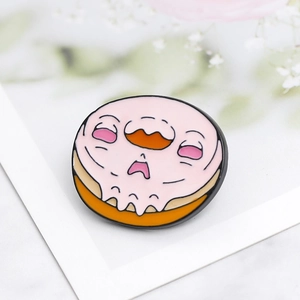 Macro shot of a pink glazed doughnut enamel pin featuring a cute crying cartoon face