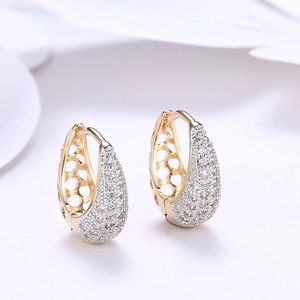 Macro shot of gold-plated hollow earrings with zircon inlay and lattice detail