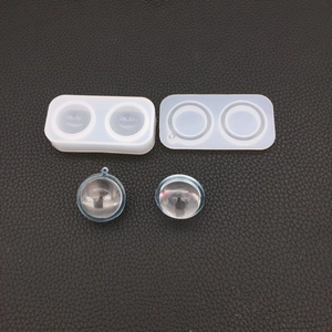 Macro view of spherical silicone resin molds and finished clear DIY pendants on black leather