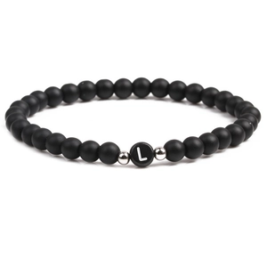 Detail of 6mm black matte stone beaded bracelet with heart letter L charm and metal beads