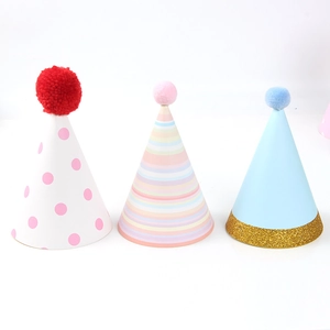Three colorful cone birthday hats with pom-poms and gold glitter for party decoration