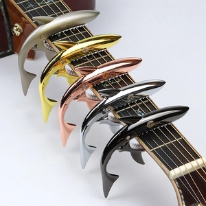 Set of 5 shark shaped zinc alloy guitar capos in multiple colors on a guitar neck