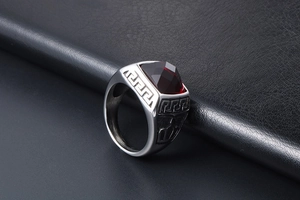 Macro detail of men's vintage steel ring with red stone and Greek key pattern