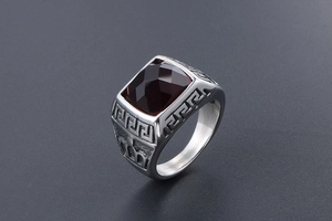 Macro view of a men's stainless steel ring with red stone and Greek key pattern engraving