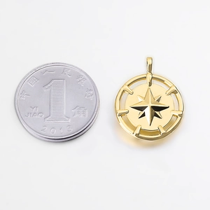 Golden compass star metal pendant with octagonal star design next to a coin for size scale