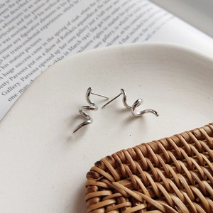 Minimalist 925 sterling silver spiral stud earrings displayed on a white plate