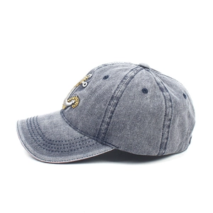 Detail of gray-blue washed denim baseball cap with gold and silver anchor embroidery