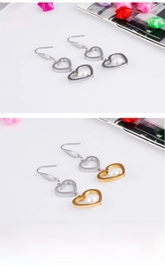 Détail de boucles d'oreilles cœurs entrelacés avec perle en placage d'or et d'argent