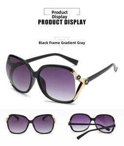 Detail view of black oversized sunglasses with golden flower hinges and gradient lenses