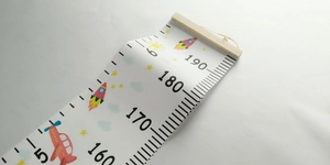 Detail view of cartoon height chart with wooden bar, rocket design and CM scale markings