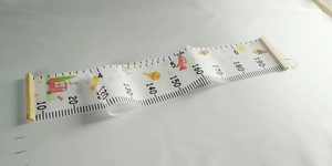 Detail of wooden hanging height chart for kids with colorful cartoon rocket and car prints