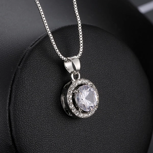 Macro shot of silver-tone halo necklace featuring a round cut zircon on a black background