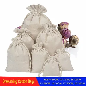 Multiple sizes of cream cotton drawstring pouches stacked with dried floral accents