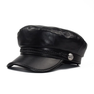 Detail of black leather baker boy hat featuring woven rope and silver metal buttons
