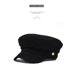 Detail of black wool newsboy cap featuring a woven band and a gold side button